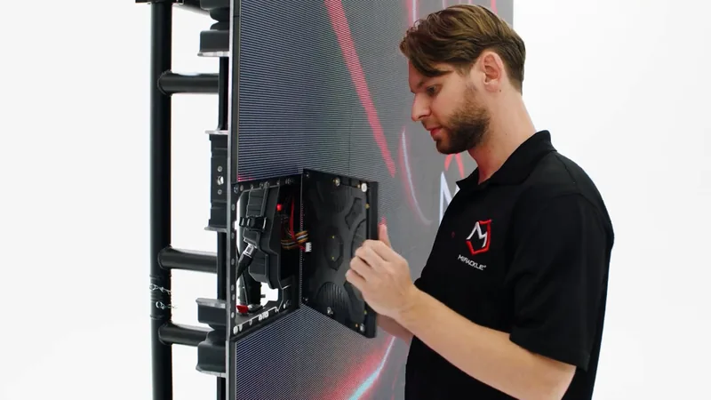 Technician in a Mirackle shirt handling an LED module on a frame